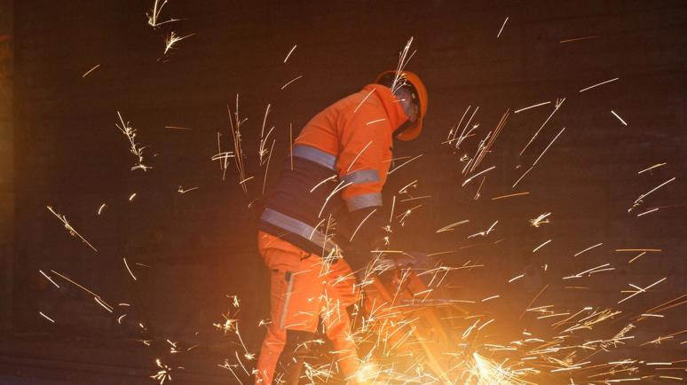 Un dipendente delle FFS in tenuta da lavoro arancione che salda